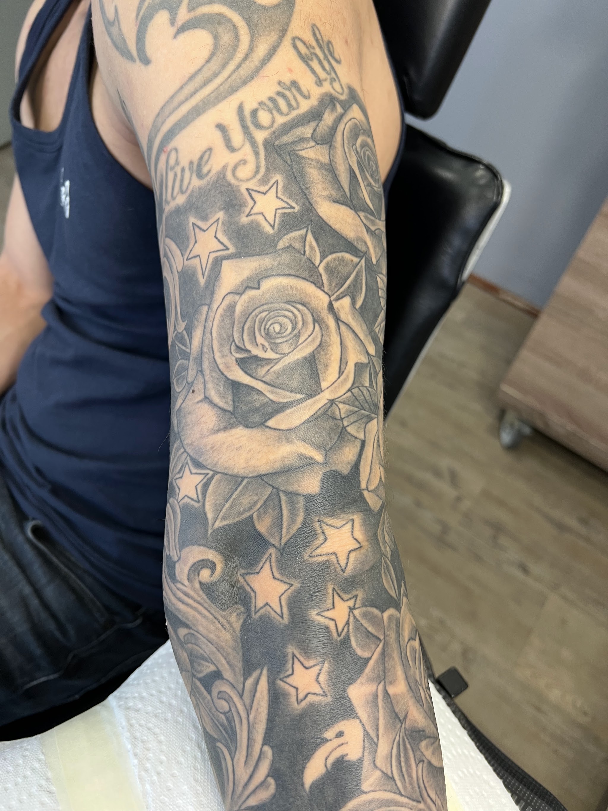 Zwart-grijze rozen en sterren in een afgewerkte armtatoeage