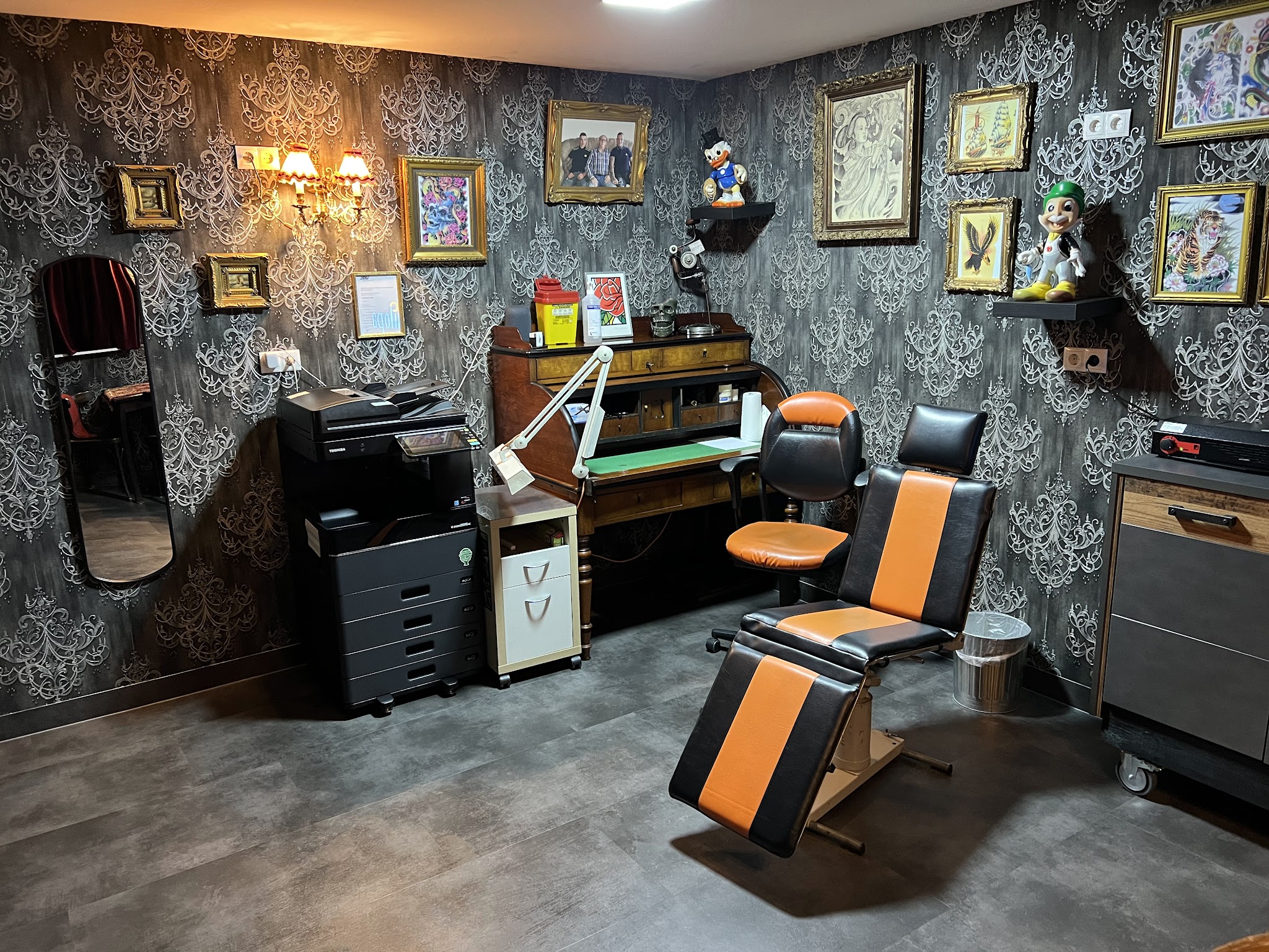 De werkruimte met tattoostoel, werkmeubels en ingelijste tattoo-illustraties