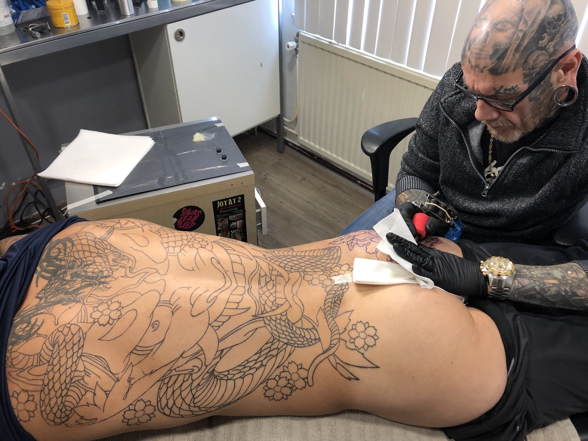 Geert werkt in zijn studio aan een grote koi-tatoeage op de rug